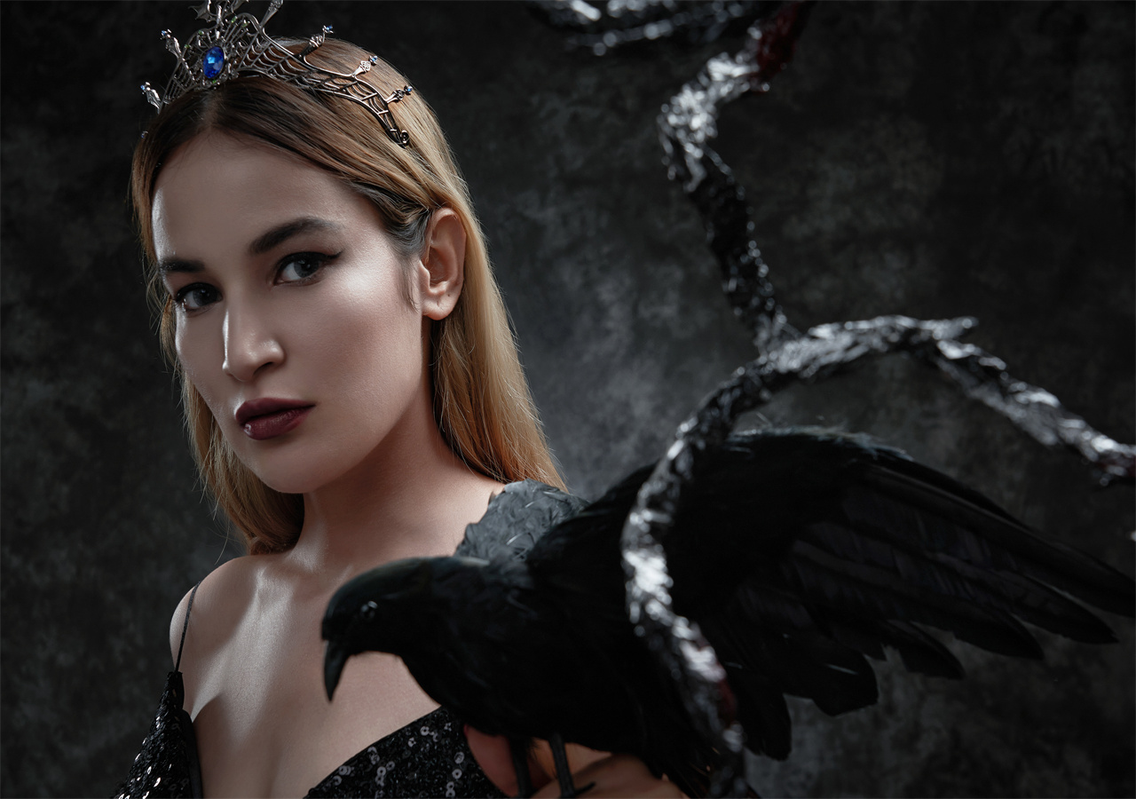 A beautiful woman is standing with a black bird