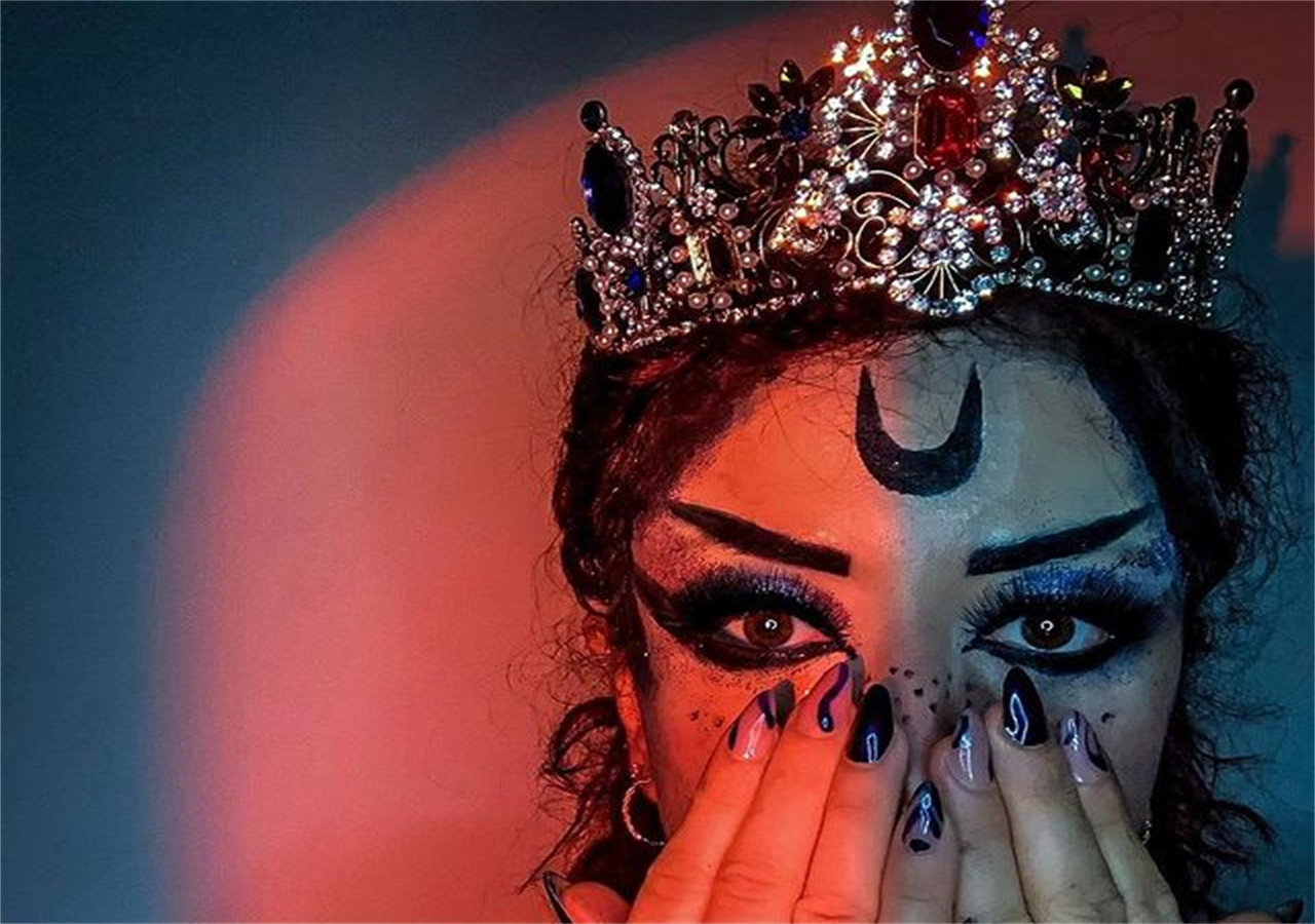 A beautiful woman with bright eye makeup and a crescent moon symbol in the middle of her forehead.