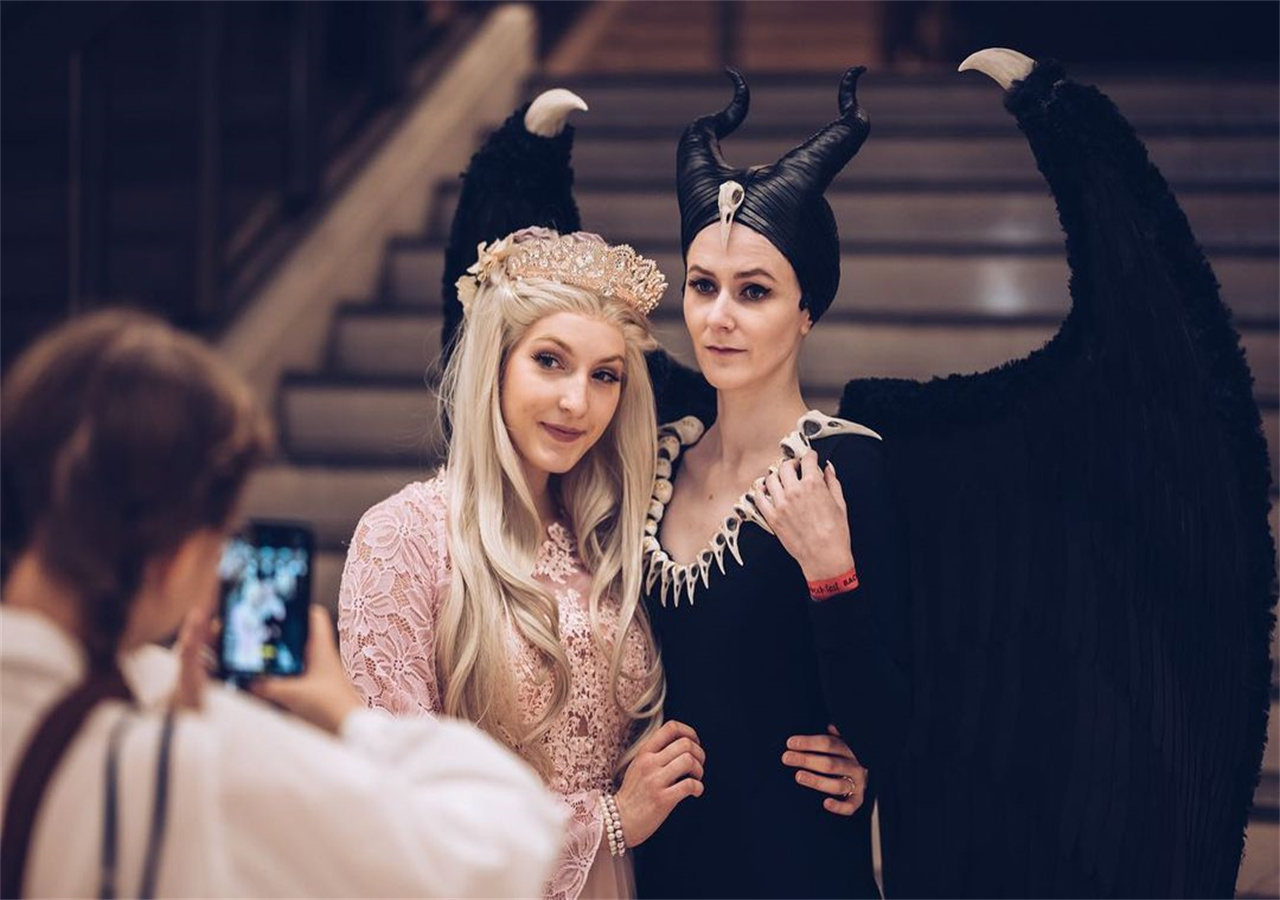 A woman is playing a role as the wicked queen, she is taking pictures with her friends.