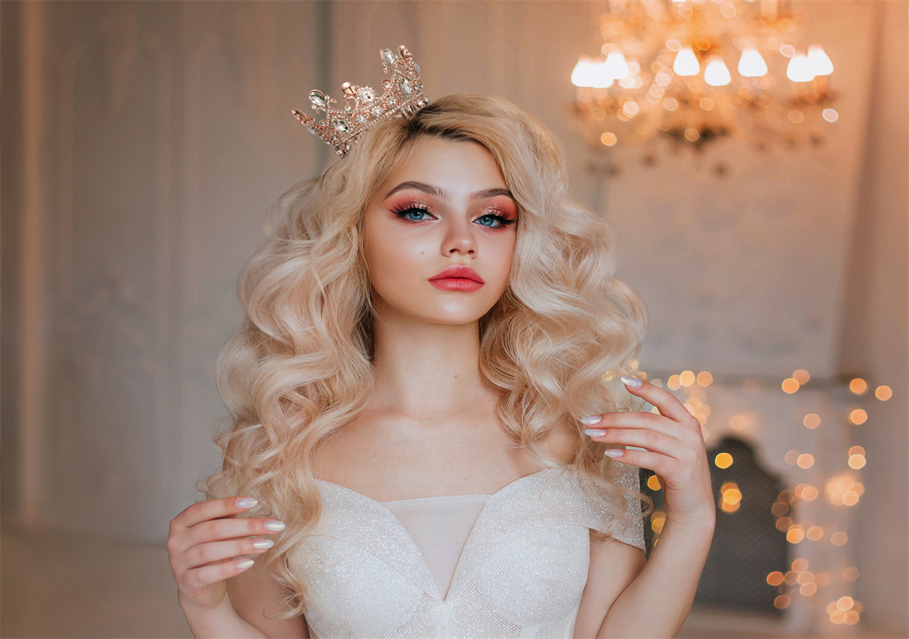 Elegant girl with long blonde wavy hair. She has a beautiful face and is wearing a Sweetv crown